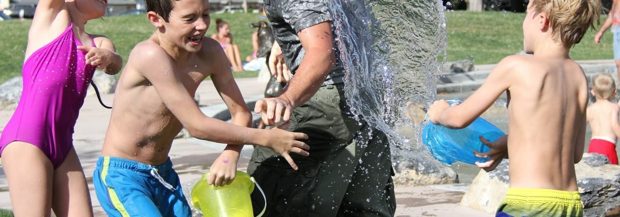kids splash adult with water at camp