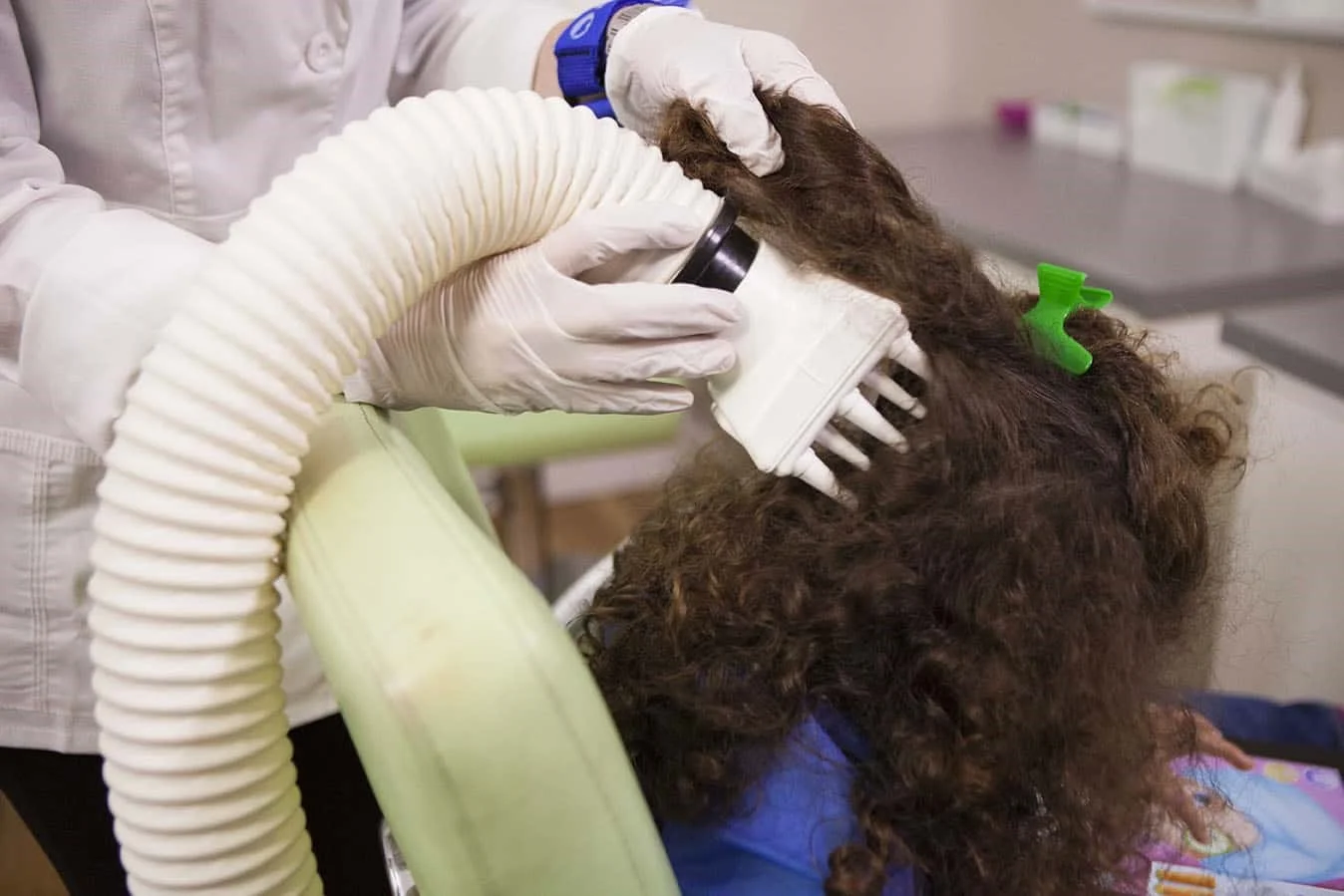 a girl receives the AirAllé head lice treatment